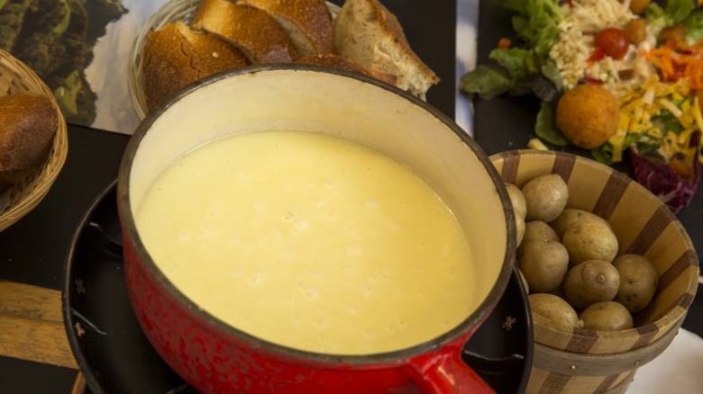 Cheese fondue pot surrounded by bread and vegetables