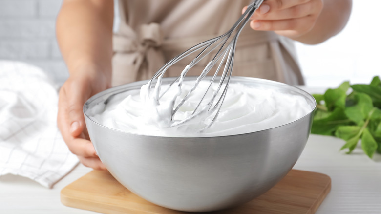 Person using balloon whisk to whip bowl of cream
