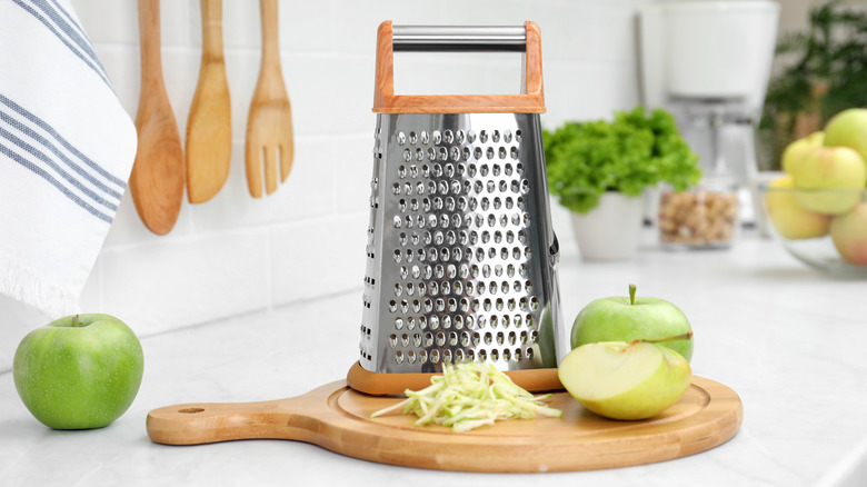 Box grater on counter next to sliced and shredded apple