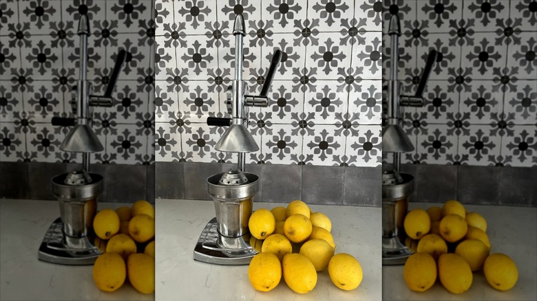 Manual citrus juicer next to pile of lemons