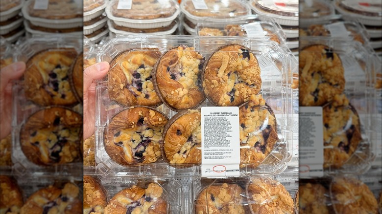 Hand holding a six pack plastic package of Costco's Blueberry Cheesecake Caramelized Croissants in bakery section