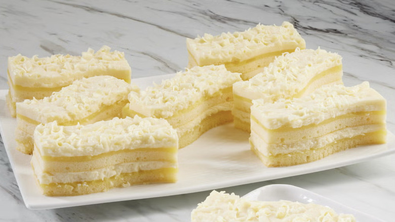 Eight pieces of layered limoncello cake from Classic Cake brand on a plate on marble surface