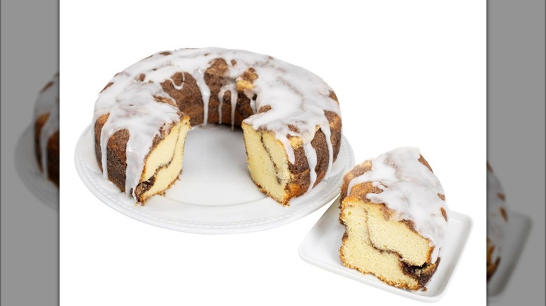slice of Collin Street Bakery Cinnamon Coffee Cake on plate next to full ring-shaped cake on plate