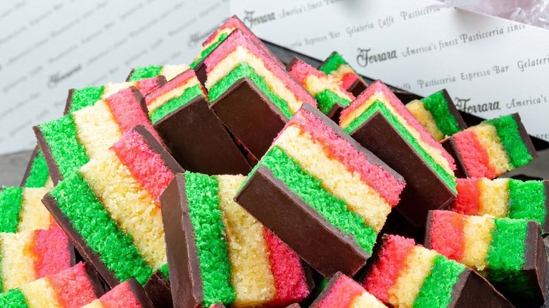Pile of Ferrara's Bakery tri color Rainbow Cookies on Ferrara gift box
