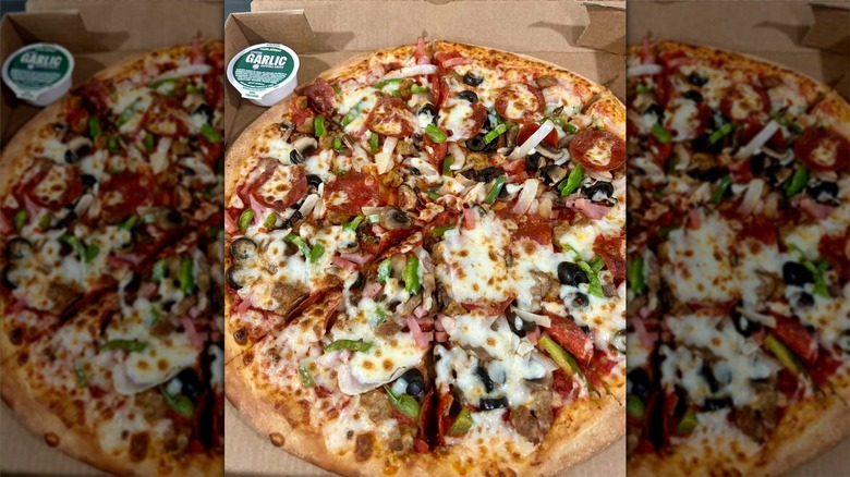 The Works Pizza in a box with garlic sauce