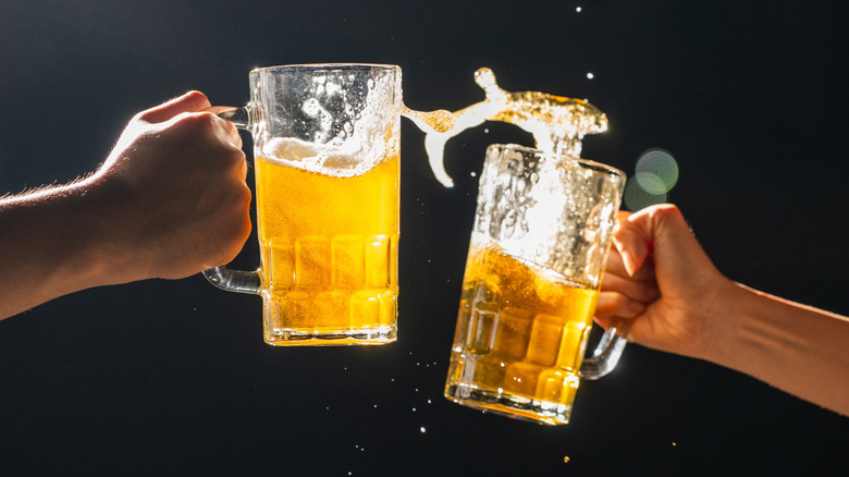 Two hands toasting with beer steins