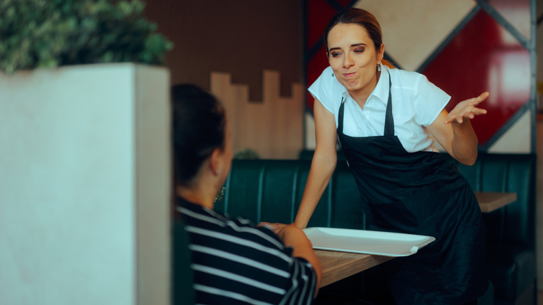Waiter shrugging while talking to customer