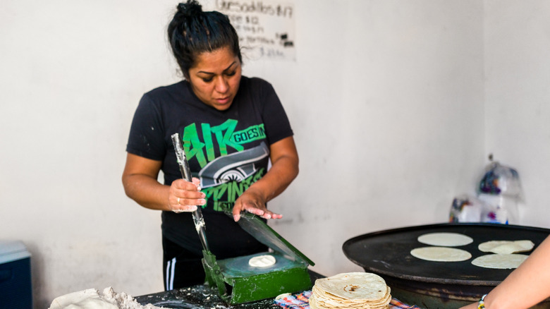 Woman making tortillas on griddle