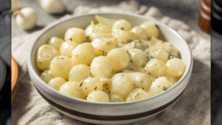 A bowl of creamed pearl onions on a table
