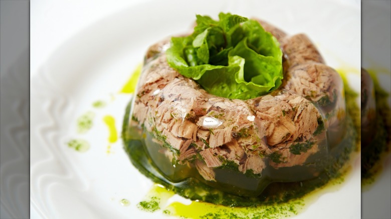 Gelatin beef salad with a lettuce garnish on a white plate