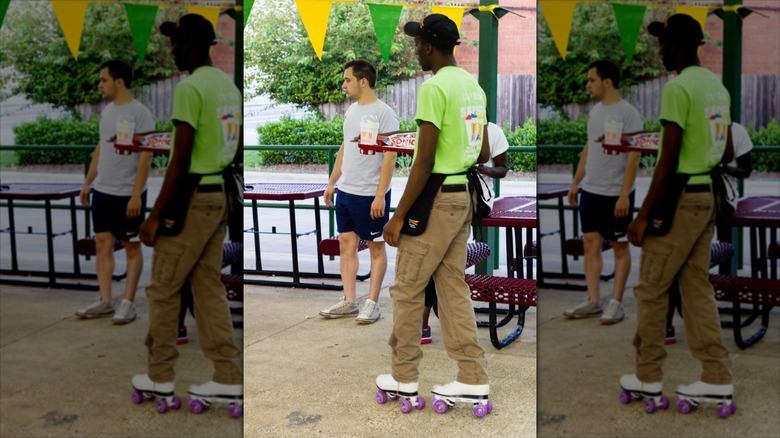 A Sonic employee ok skates carrying a tray of food