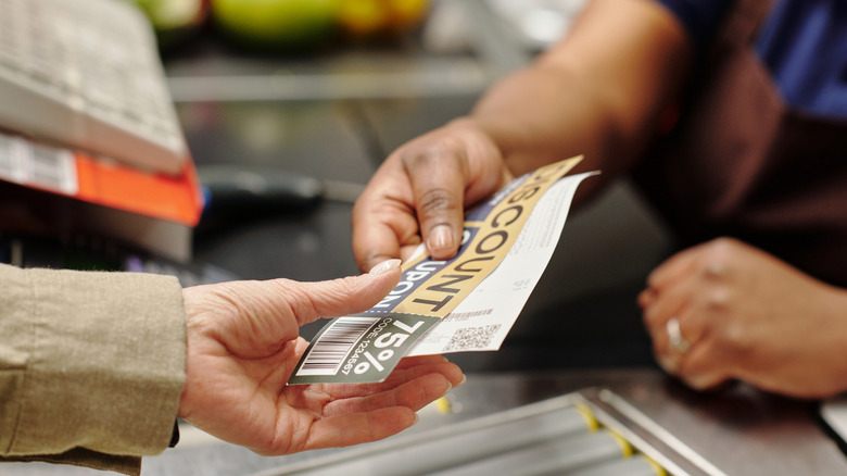 Shopper hands over a discount coupon to cashier