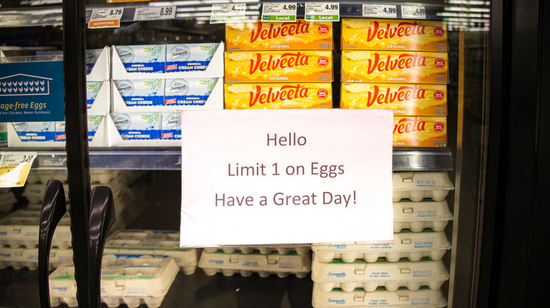 Grocery store paper sign showing a limit of one box on eggs on refrigerated dairy aisle