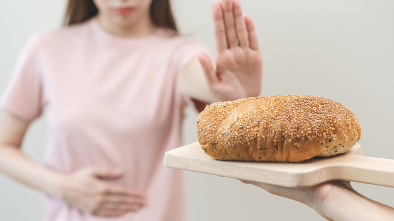 A person holding their hand up while being offered bread.