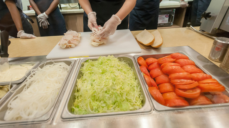 A Jersey Mike's employee in front of the sandwich ingredients.