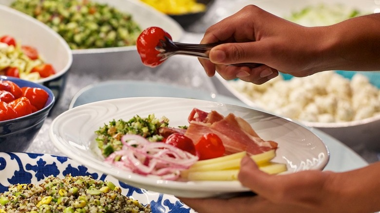 The hand of a person taking food from the Market Table