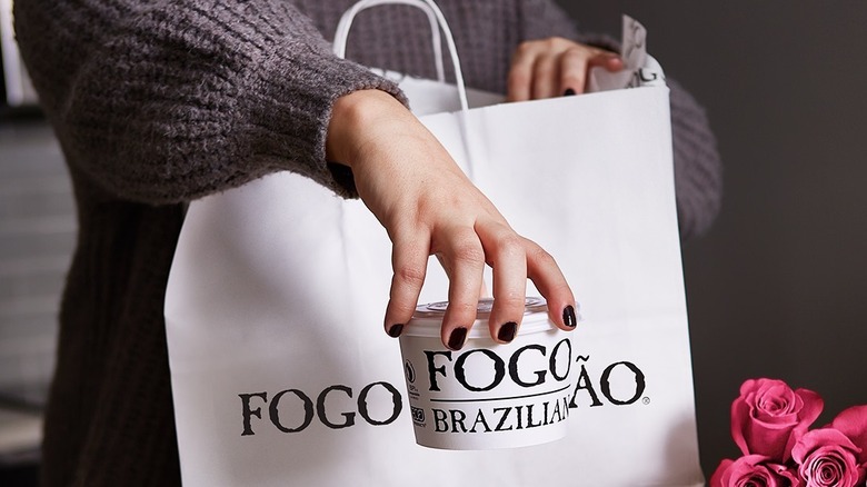 Woman taking Fogo de Chão to go out of a bag