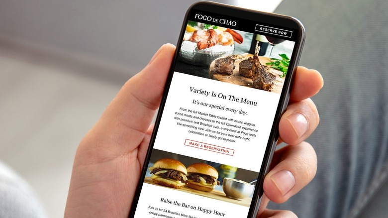 Hand holding an iphone to make a reservation on the Fogo de Chão app