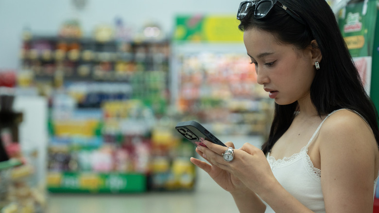 Woman using phone in grocery store