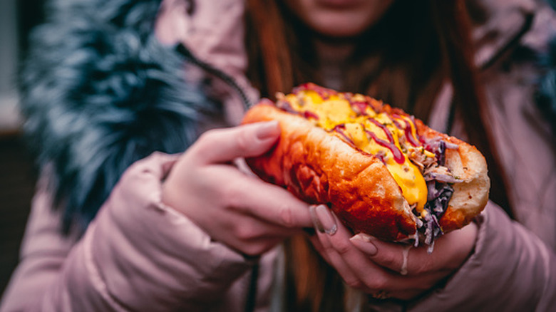 close up of a woman holding a Philly cheesesteak sandwich