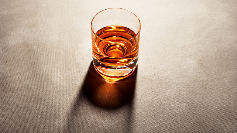 A glass of neat whiskey casting a shadow