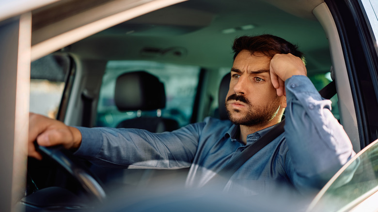Man waiting in car, looking annoyed
