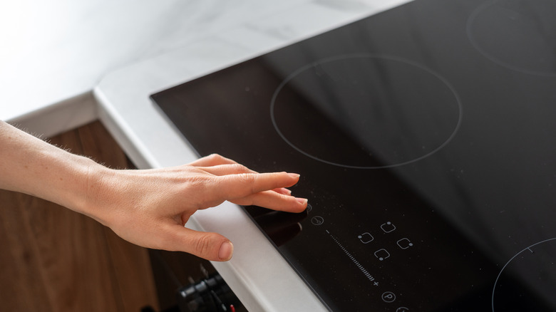 A hand adjusting the settings on an electric stove