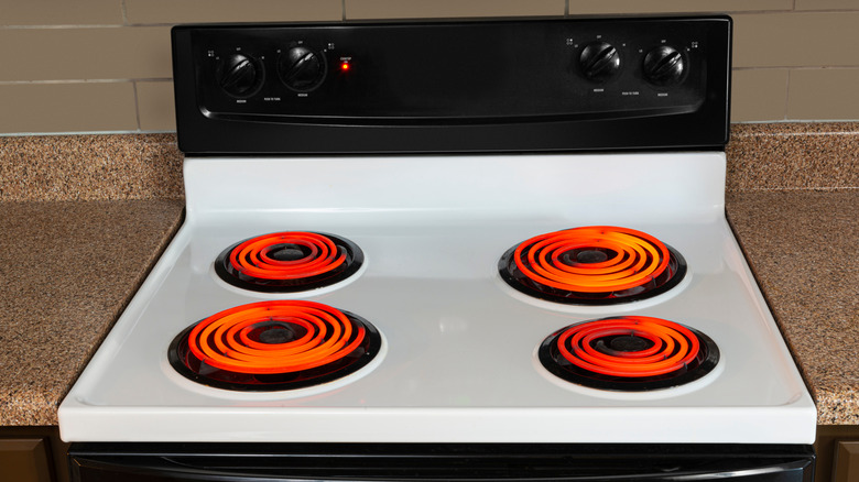 An electric cooktop without the lid, revealing glowing red coils