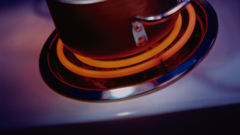 Water in pot boiling vigorously on glowing electric burner