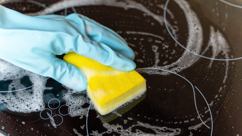 gloved hand scrubbing an electric stovetop