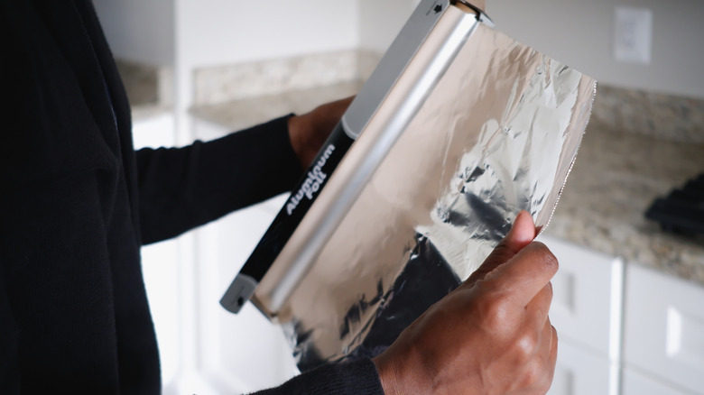 hands holding a roll of aluminum foil