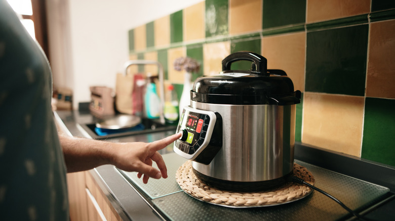 A home cook setting a timer on a slow cooker