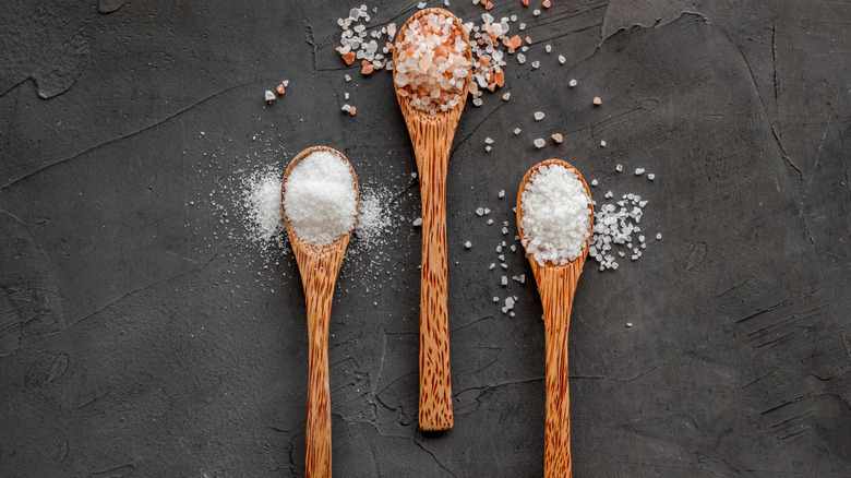 Three small wooden spoons each containing a different tyle of salt