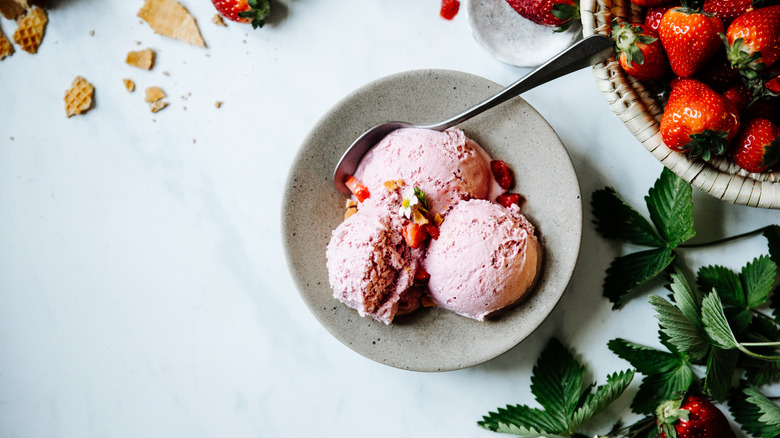 Bowl of strawberry ice cream next to fresh strawberries