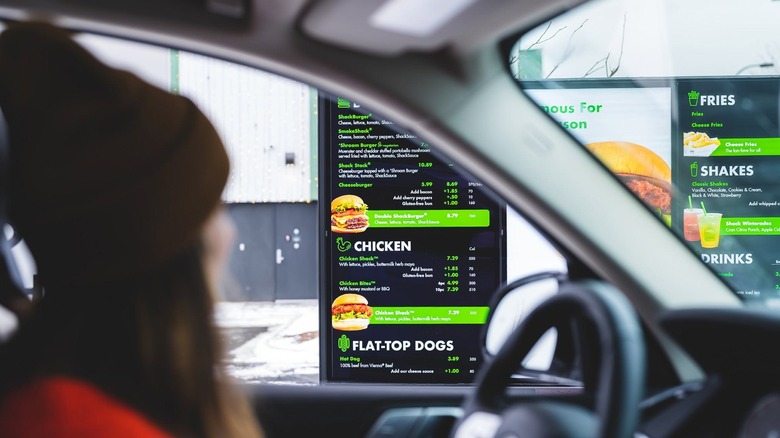 A woman examines the Shake Shack drive-thru menu from her car.