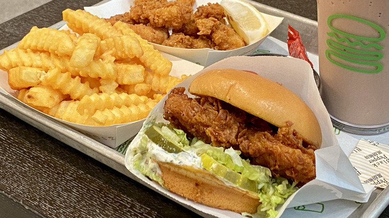 A Shake Shack chicken sandwich sits on a tray with fries and a shake.