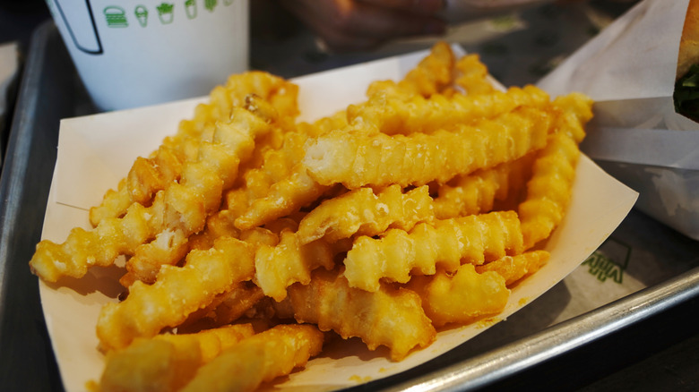 Golden-brown Shake Shack fries sit in a paper boat.