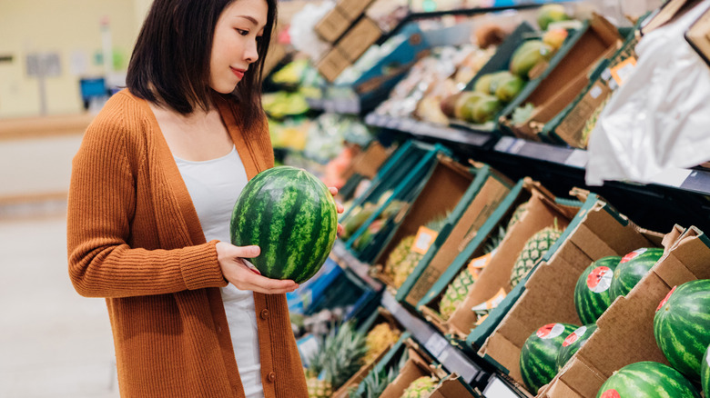 woman holding watermelon in grocery store