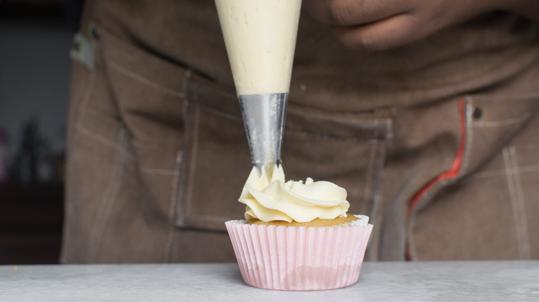 Piping frosting onto a vanilla cupcake