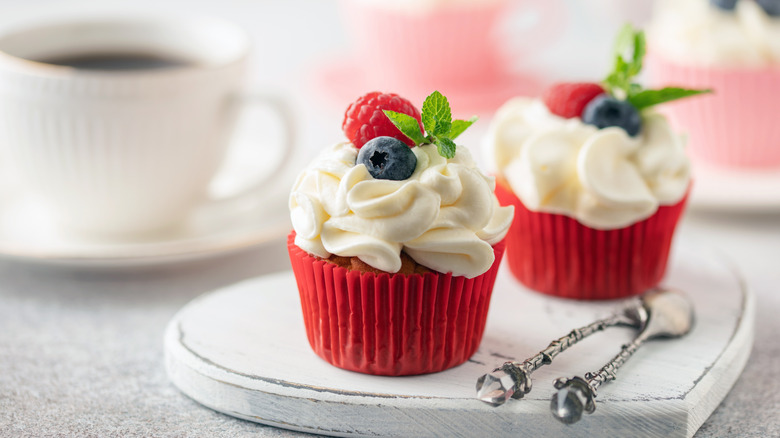 Cupcakes with white frosting topped with fresh blueberries, raspberries, and a sprig of mint