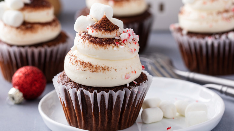 Chocolate cupcakes with white frosting, cocoa dusting, peppermint chips, and marshmallows