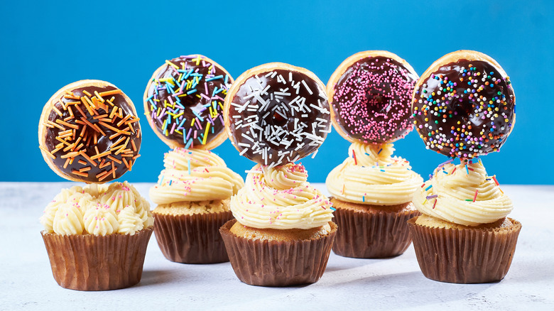 Vanilla cupcakes with white frosting topped with mini donuts