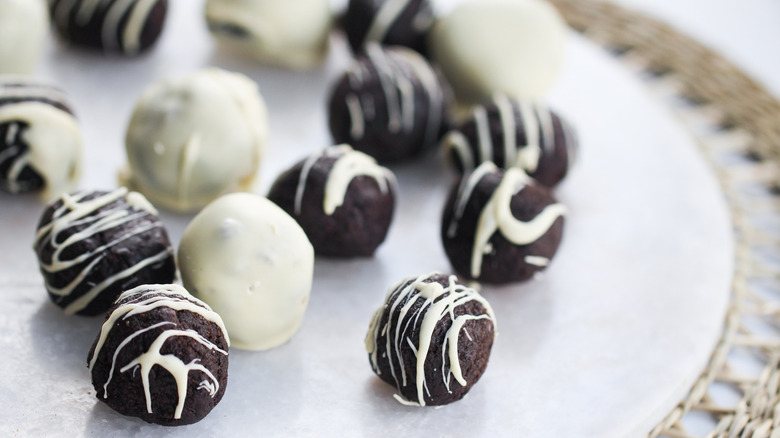 Oreo truffles (some fully coated in white chocolate) sitting on greaseproof paper 