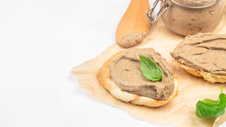 Chicken liver mousse spread on top of a piece of bread, on brown paper.