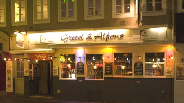 Street view of a pub at night with a lighted sign that reads Gretel and Alfons.