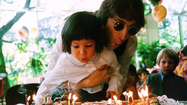 John Lennon holds his son Sean as they blow out the candles on a birthday cake.