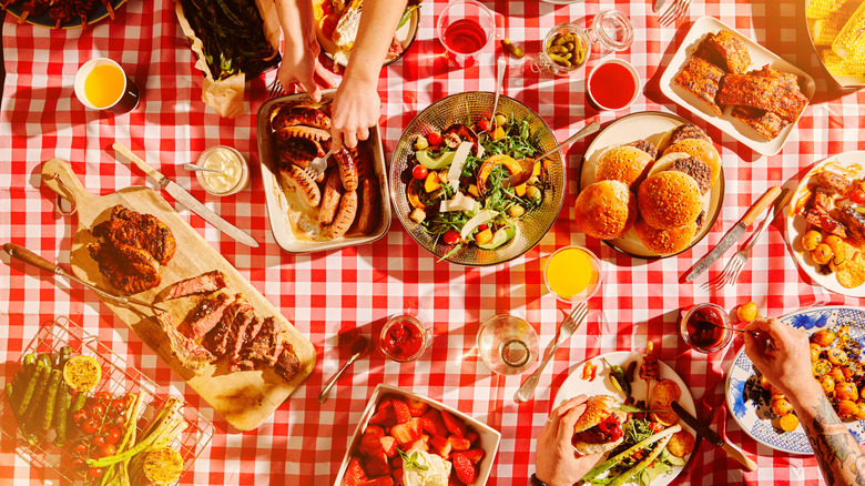 Picnic table with assorted food, drinks, and condiments