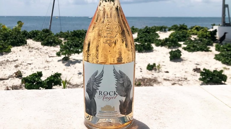 Bottle of Rock Angel with sand and water behind