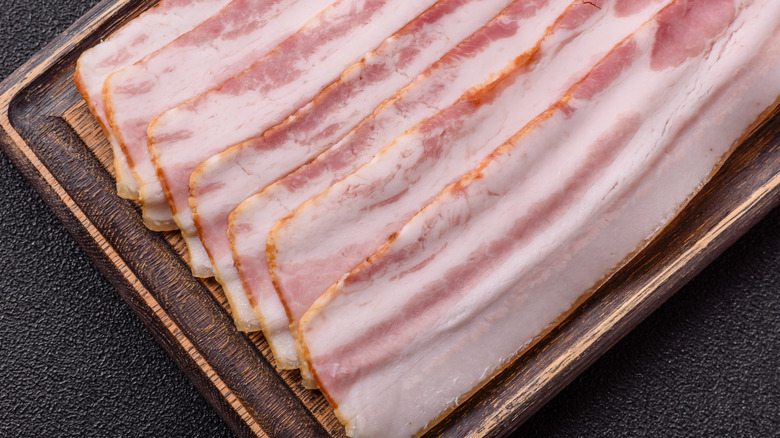 Raw bacon on a wooden board