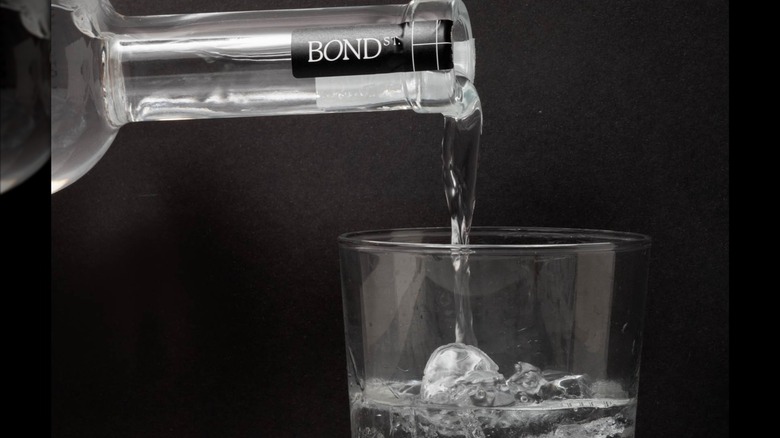 bottle of vodka being poured into a glass over ice